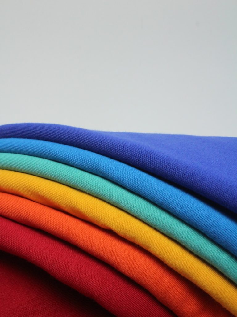 a stack of different colored t - shirts sitting on top of each other